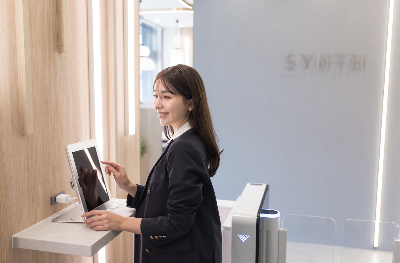 受付前でタブレットを操作する女性。